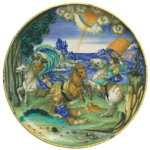 A shallow maiolica bowl with a painting of two men riding white horses and a third man who had fallen from his brown horse on the ground. In the sky above, the sun appears from behind clouds, with a ray directed toward the man on the ground. The scene depicts the biblical story of the conversion of Saul.