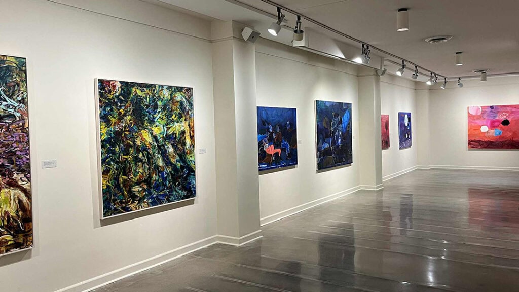 Gallery wall featuring colorful exhibition paintings.